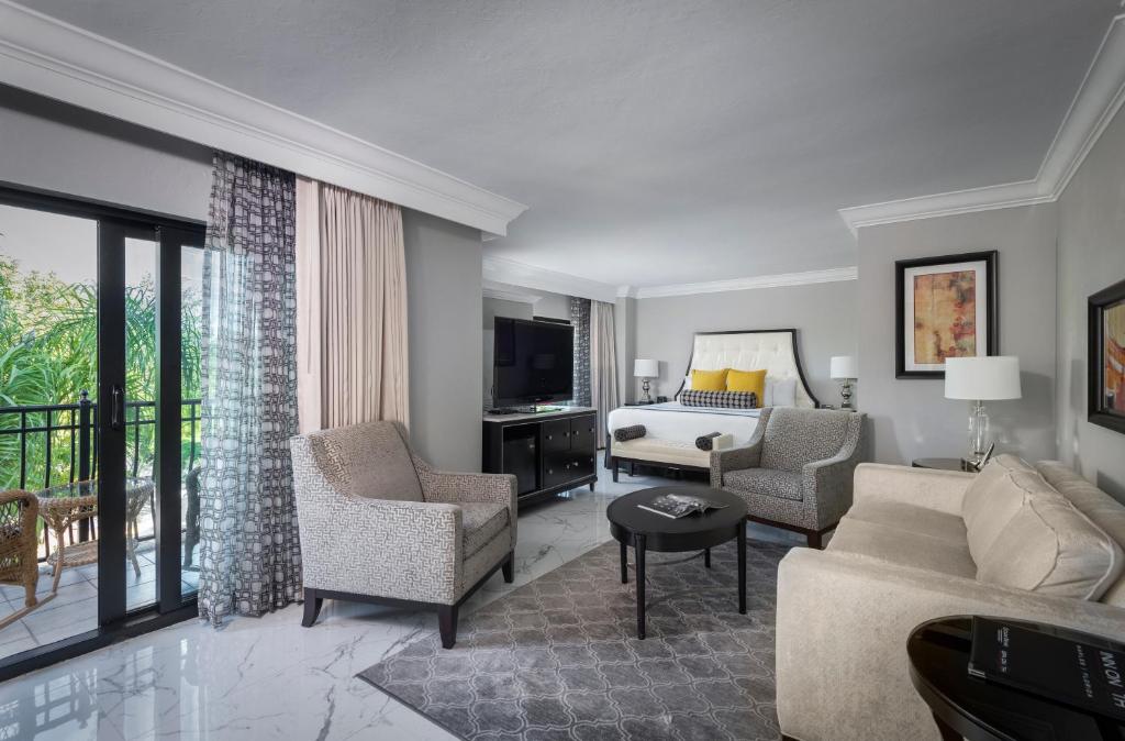 a living room with a couch and chairs and a television at Inn On Fifth in Naples