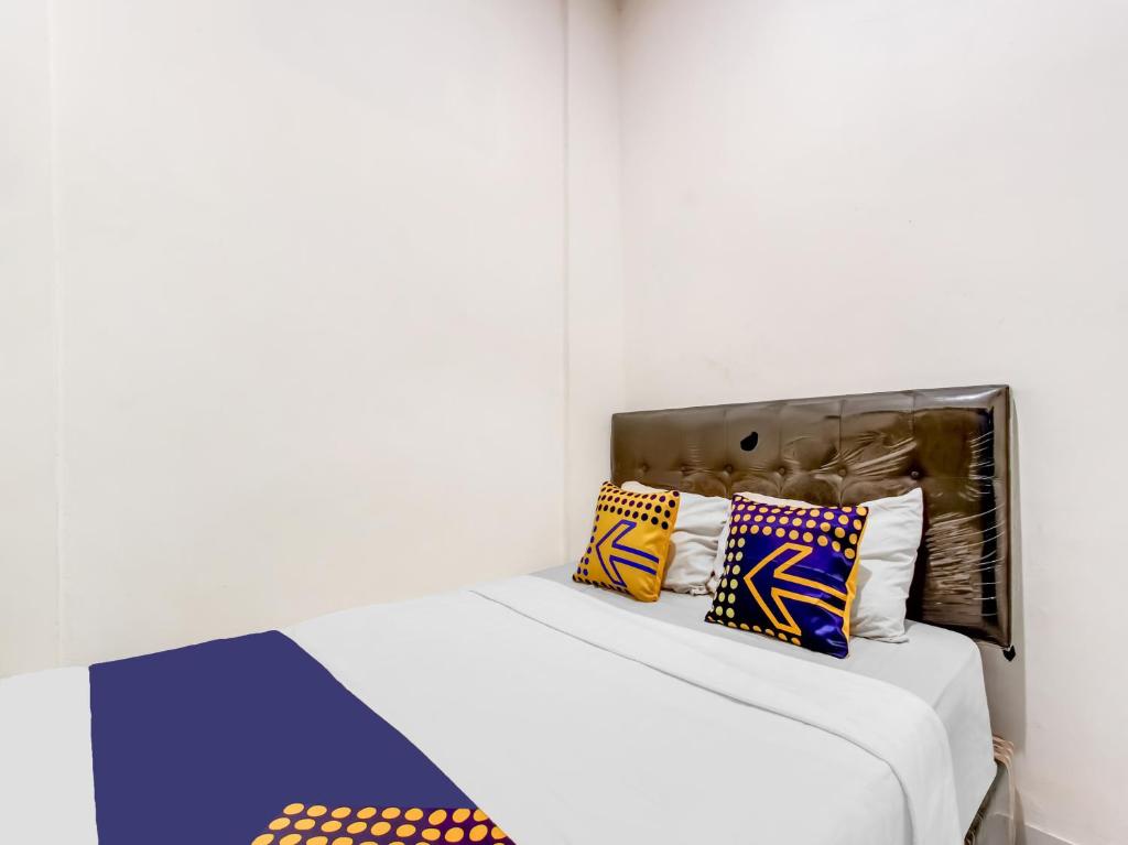 ein weißes Zimmer mit einem Bett mit bunten Kissen in der Unterkunft OYO Life 91374 Asia Stay Semarang Syariah in Semarang