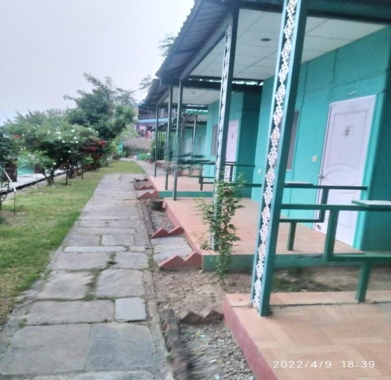a blue building with benches in front of it at Kedar Heights Heli Resorts by StayApart in Phata