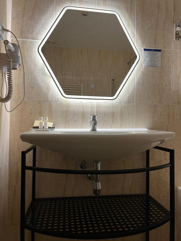 lavabo en el baño con espejo grande en la pared en Hotel Suites Feria de Madrid, en Madrid