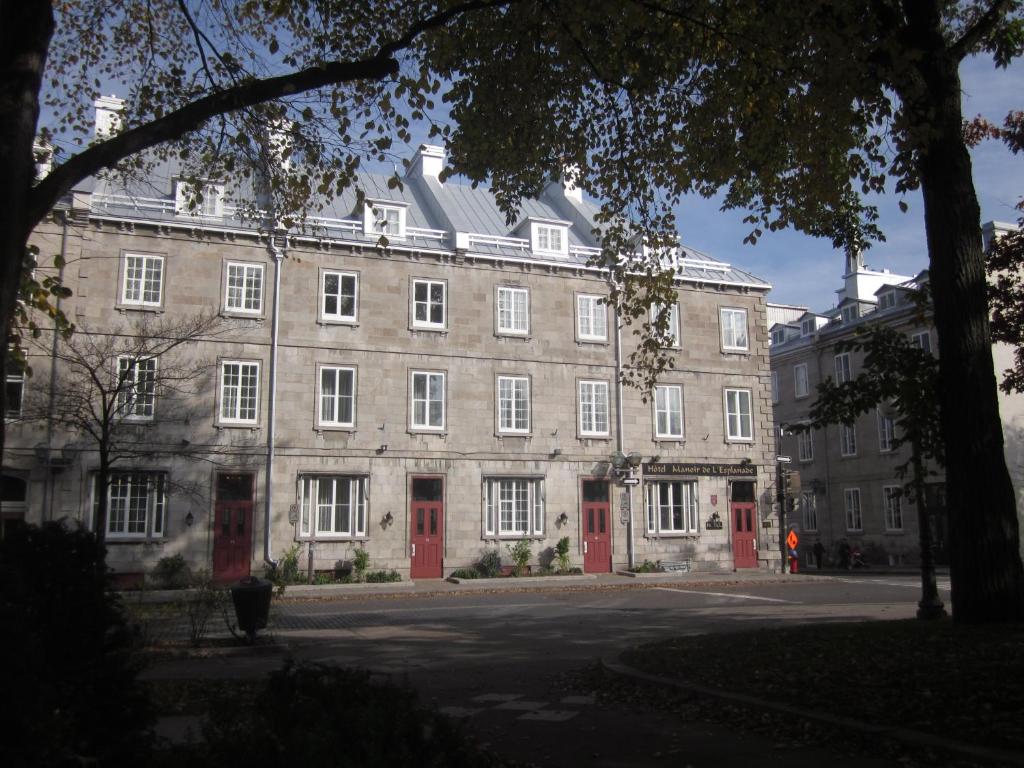 a large stone building with red doors on a street at Hôtel Manoir de l'Esplanade in Quebec City