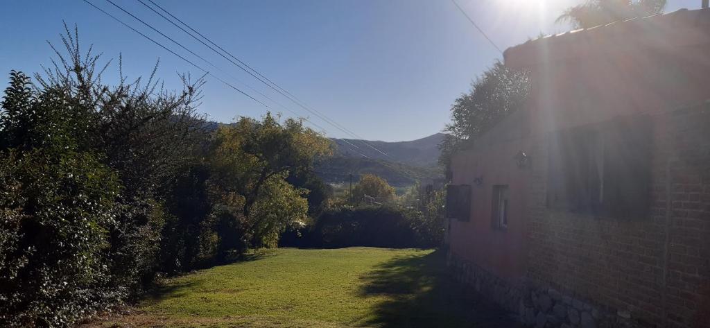 une maison avec une cour herbeuse à côté d'un bâtiment dans l'établissement Casa con vista a la salida del sol, à La Cumbre