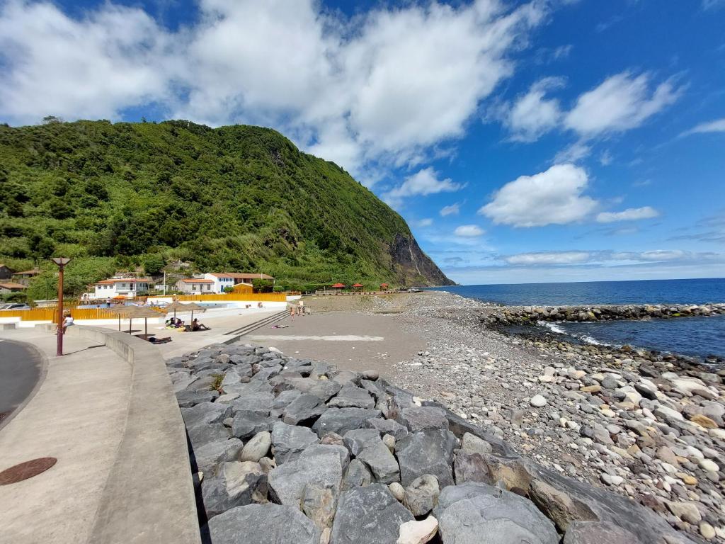una spiaggia con rocce e l'oceano e una montagna di Casa do sanguinho a Faial da Terra