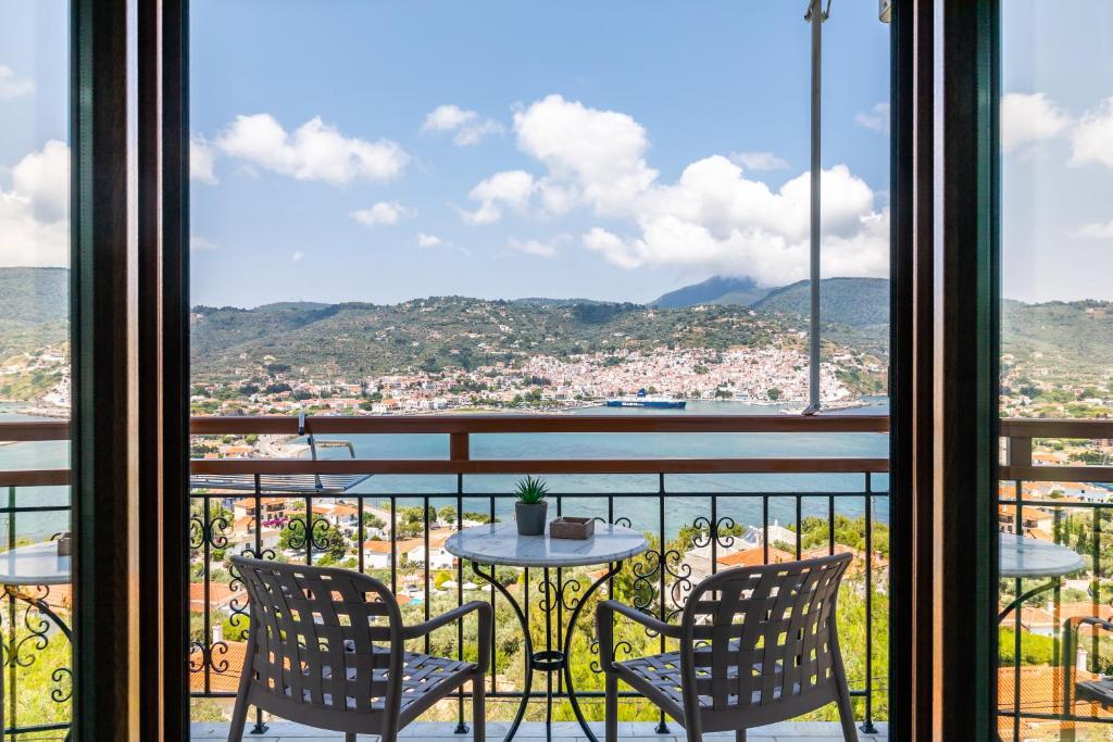 balcón con mesa, sillas y vistas a la ciudad en Aegeon Hotel en Skopelos Town