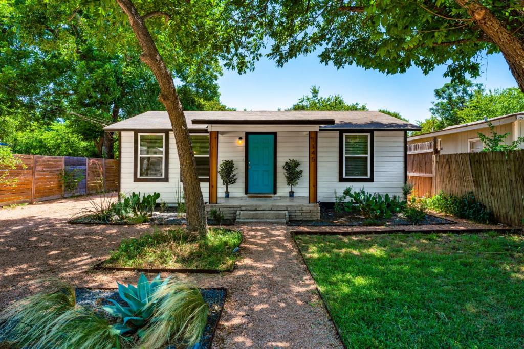 una pequeña casa blanca con una puerta azul en New! Entire House, 5 Minutes from downtown, en San Marcos
