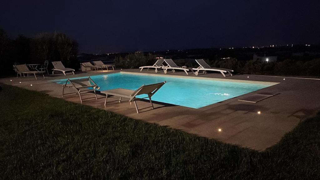 una piscina por la noche con sillas alrededor en Villa Dyria exclusive swimming pool, en Monopoli