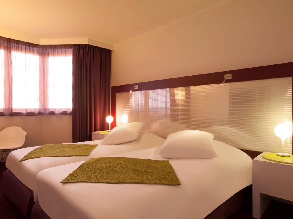 a hotel room with two beds with white sheets at Mercure Strasbourg Centre in Strasbourg