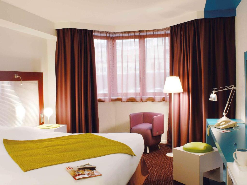 une chambre d'hôtel avec un lit et une chaise dans l'établissement Mercure Strasbourg Centre, à Strasbourg