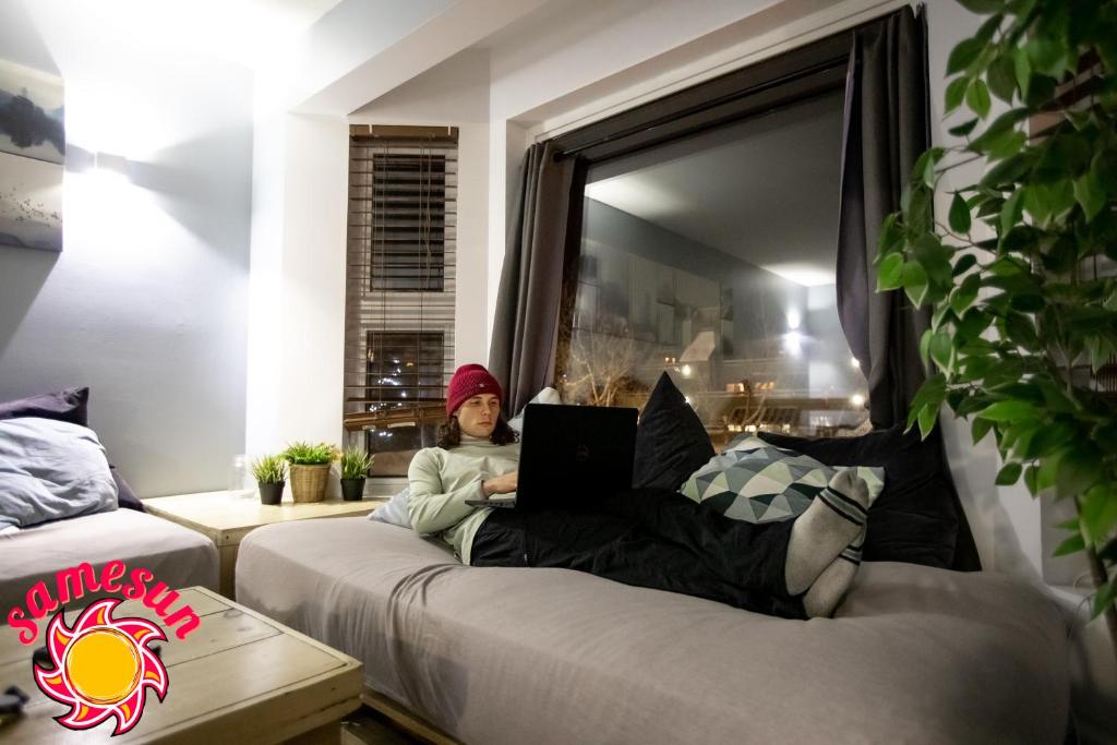 a young girl sitting on a couch with a laptop at Samesun Banff Hostel in Banff