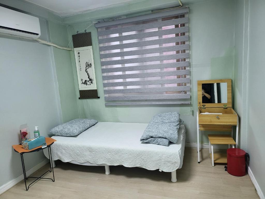 a bedroom with two beds and a window with a mirror at MK Guesthouse in Busan