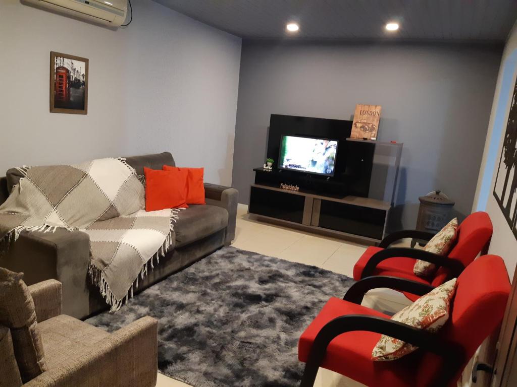 a living room with a couch and a tv at Apartamento London - Centro Nova Petrópolis in Nova Petrópolis