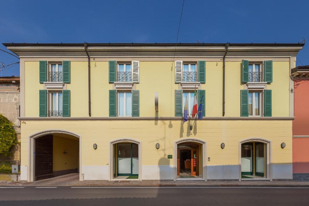 ein gelbes Gebäude mit grünen Rollläden in der Unterkunft Hotel Gambara in Gambara