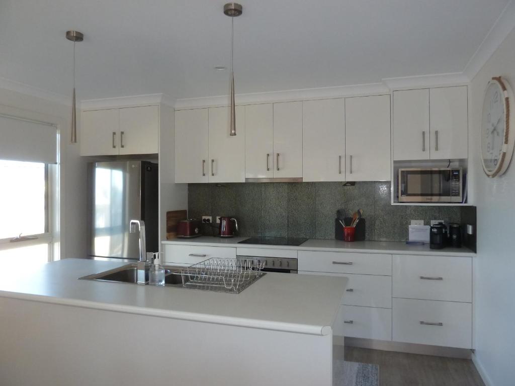 a kitchen with white cabinets and a sink at Westwood Villas - Unit 2 in Bridport