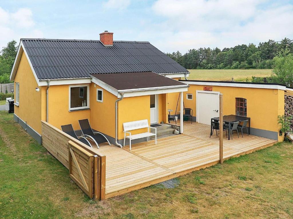 a house with a wooden deck in the yard at 5 person holiday home in L s in Læsø