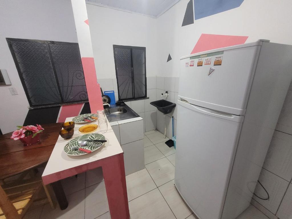 uma pequena cozinha com um frigorífico e uma mesa em Romulo Ap3 em Manaus