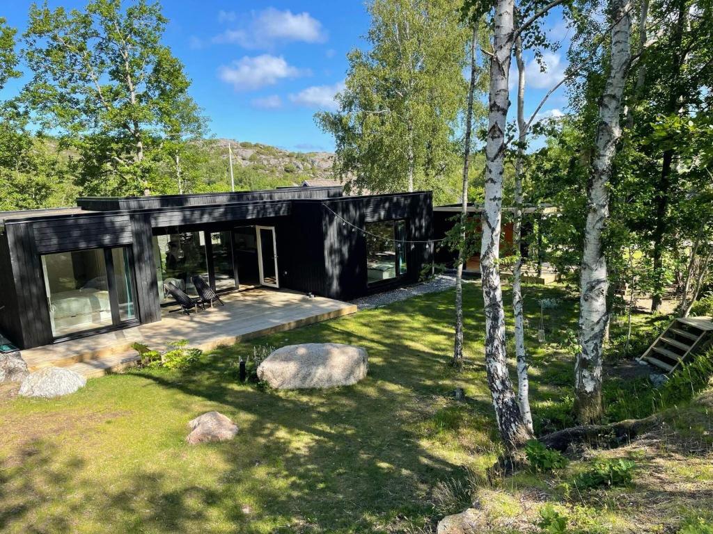 uma casa negra na floresta com árvores em Holiday home HÄLLEVIKSSTRAND V em Hälleviksstrand