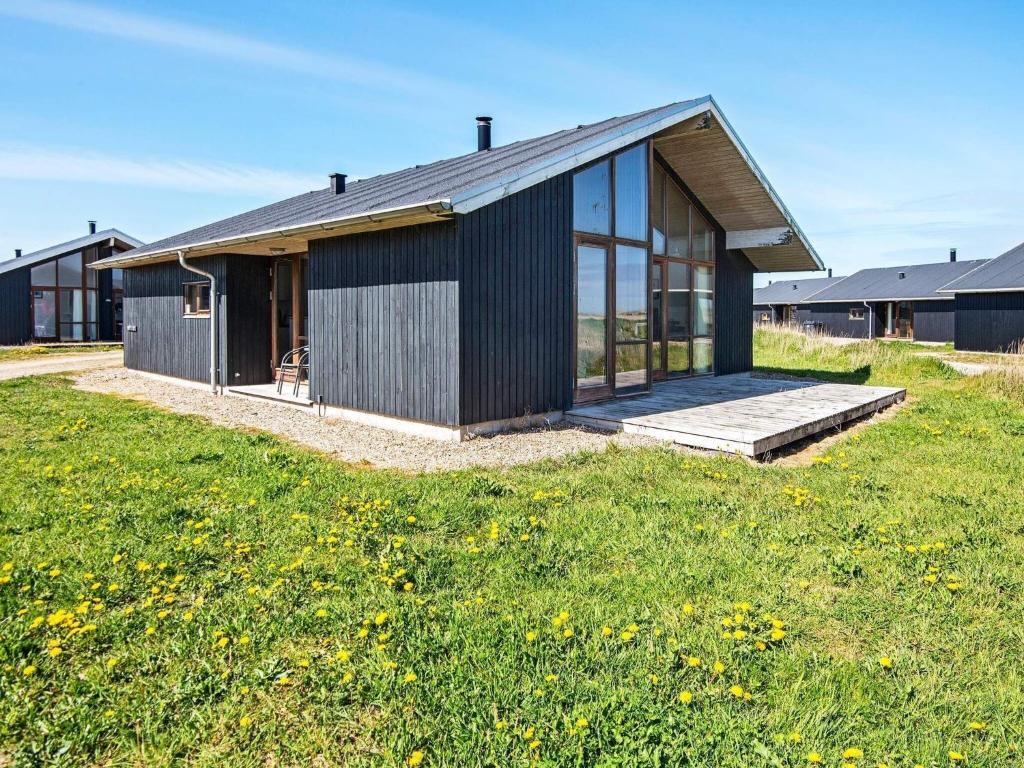 dom z czarną fasadą i trawnikiem w obiekcie 8 person holiday home in Ulfborg w mieście Ulfborg