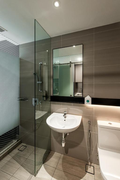 a bathroom with a sink and a shower and a toilet at Komune Living in Kuala Lumpur