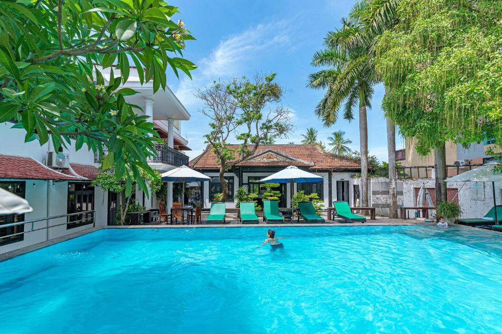uma pessoa na piscina de um resort em Nostalgia Hotel and Spa em Hoi An