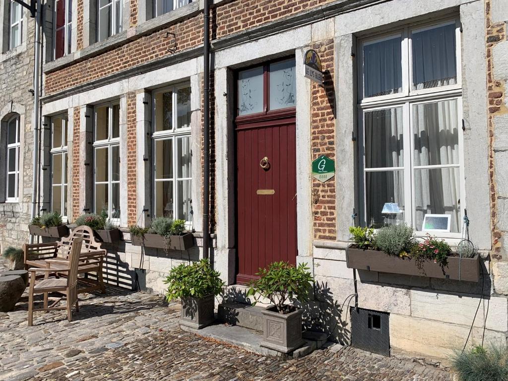 eine rote Tür auf einem Backsteingebäude mit Topfpflanzen in der Unterkunft Gite de Caractère Le Lys Bleu in Limbourg