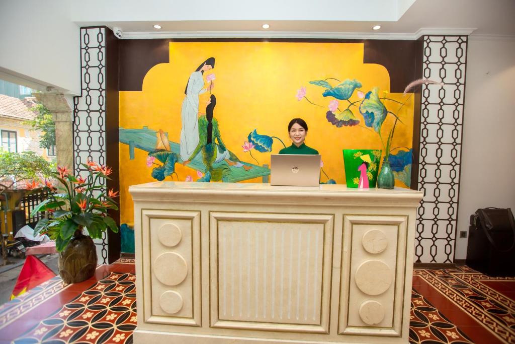 a woman is sitting at a desk with a laptop at Hanoi Center Silk Boutique Hotel & Travel in Hanoi