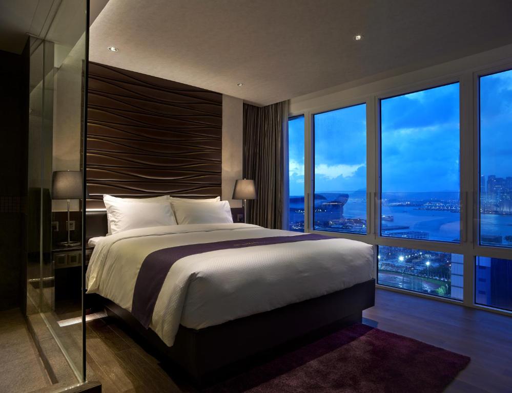 a bedroom with a large bed and large windows at Crafa Harbour Hotel in Hong Kong