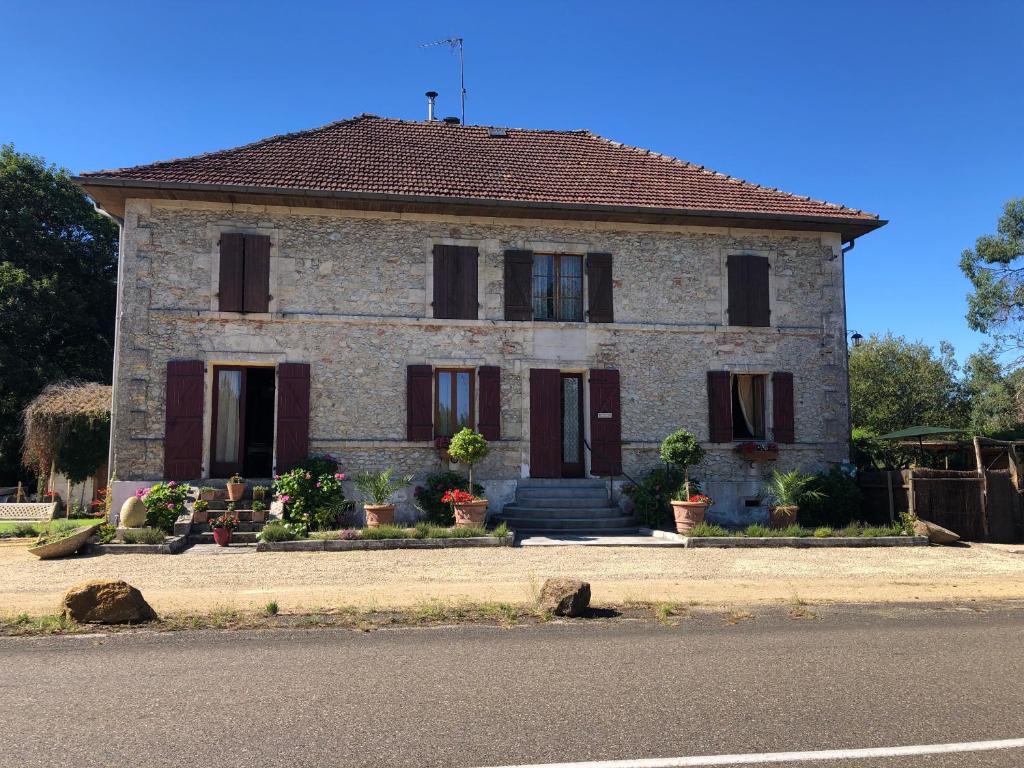 a large stone house with red shutters on a street at la maison des ateliers in Solférino