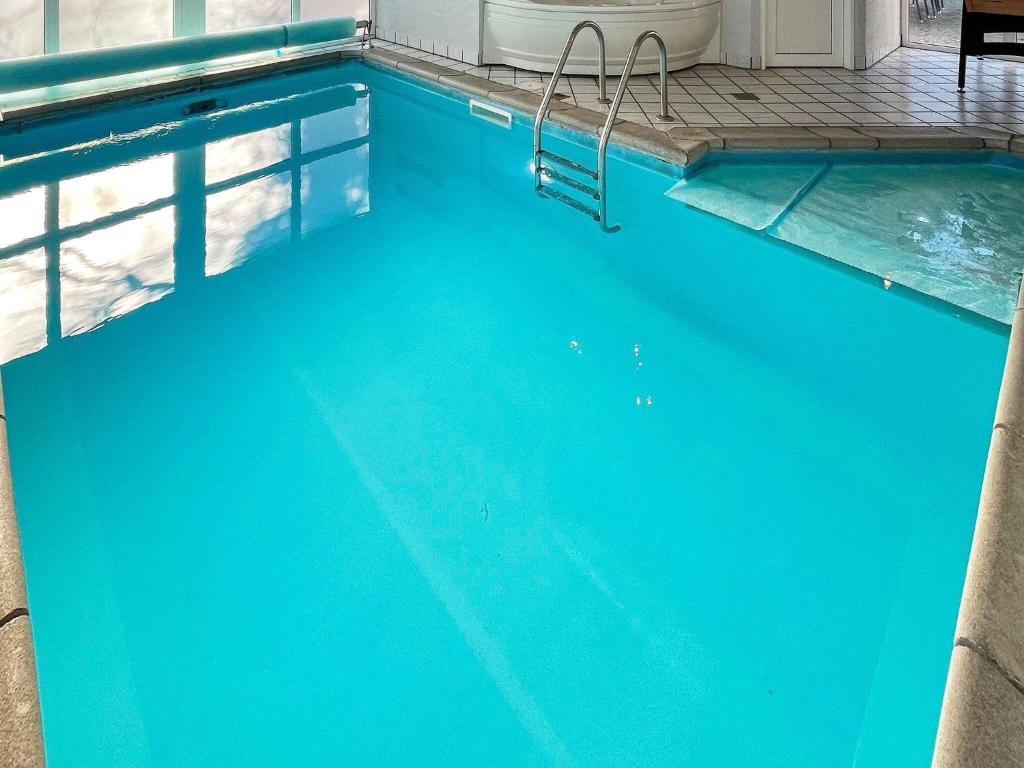 a large blue swimming pool with a chair in it at 10 person holiday home in Glesborg in Fjellerup Strand