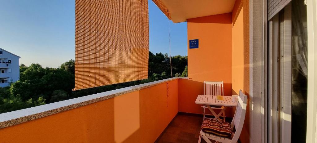 einen orangen Balkon mit einem Tisch und Stühlen darauf in der Unterkunft Apartment Mani - modern in Ližnjan