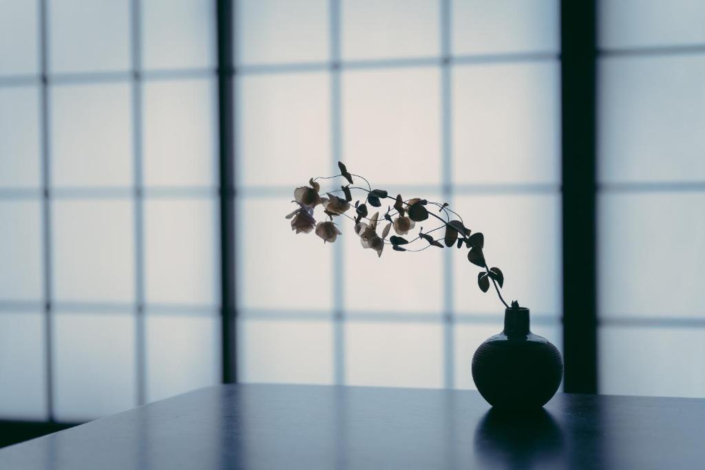 a vase with a flower in it on a table at Kotone Machiya-Inn 京町家旅宿 小都音 in Kyoto