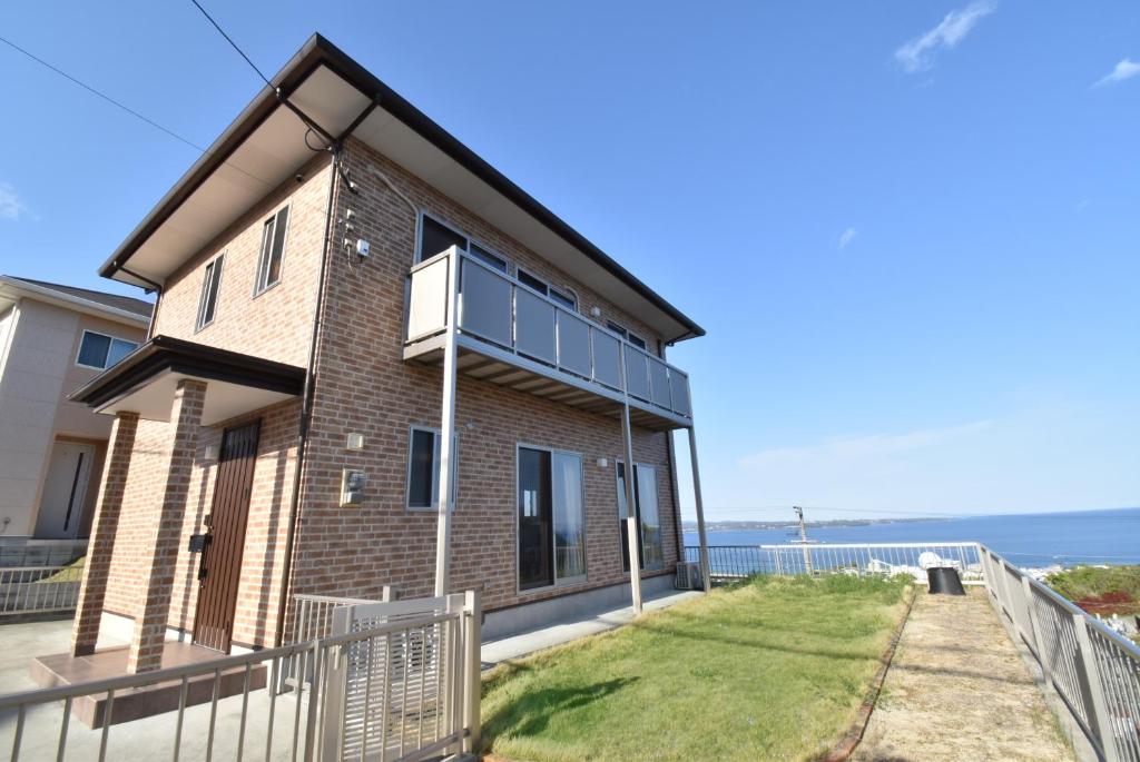 a house with a balcony with the ocean in the background at Bep one the house with ocean view in Kamegawa
