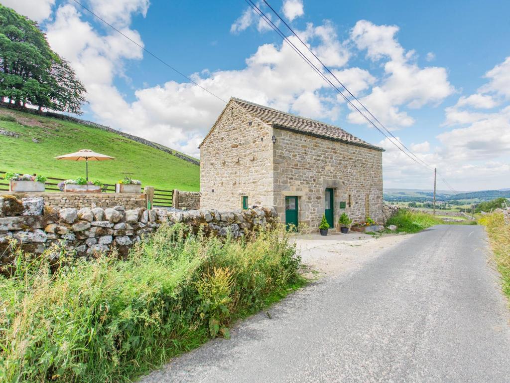 a stone building with an umbrella on the side of a road at Pogles Wood Cottage in Skipton