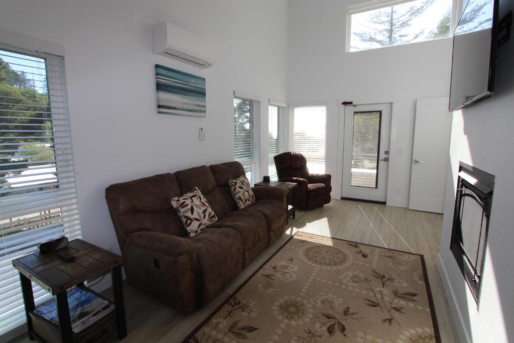 a living room with a brown couch and two chairs at The Springs at Deerhaven in Gold Beach