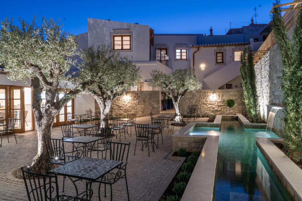a courtyard with tables and chairs and a swimming pool at Eleven, Boutique luxury house & garden in Boliqueime