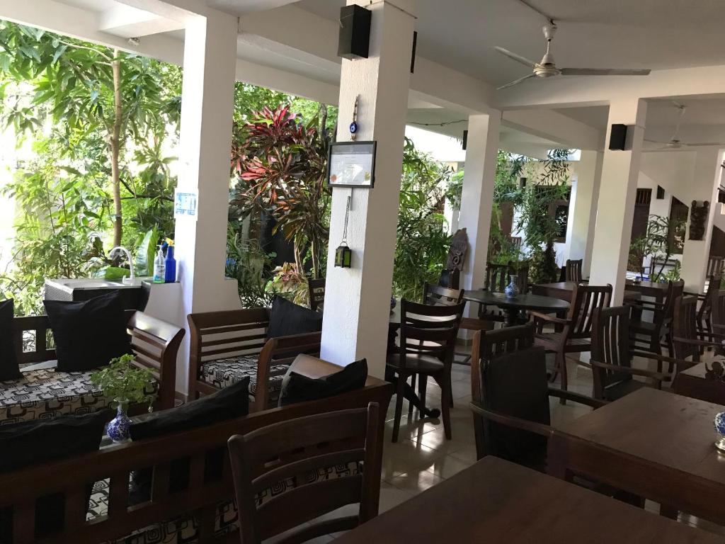 a restaurant with tables and chairs and plants at Unawatuna Beach Bungalow - in Unawatuna
