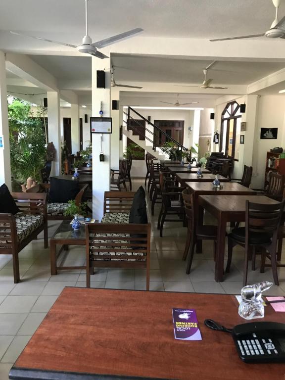a restaurant with wooden tables and chairs in a room at Unawatuna Beach Bungalow - in Unawatuna