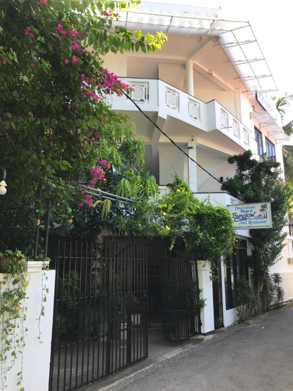 a building with a black gate and flowers at Unawatuna Beach Bungalow - in Unawatuna
