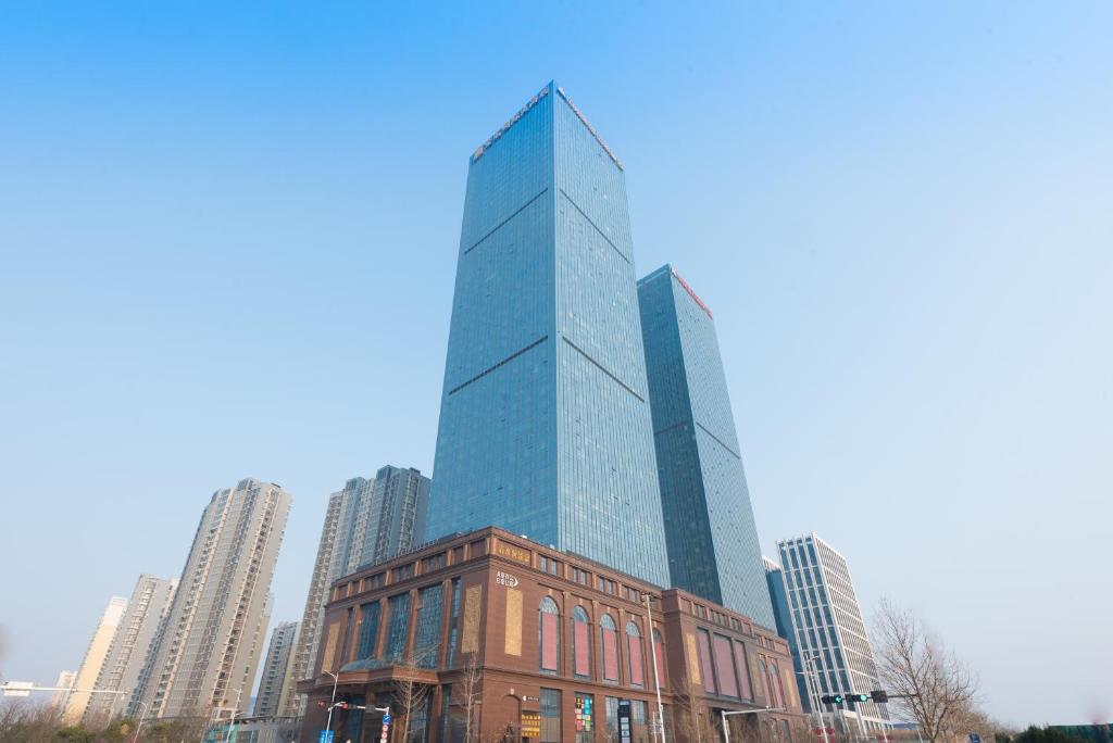 a tall glass building in the middle of a city at Qingdao Jinshi International Hotel in Qingdao