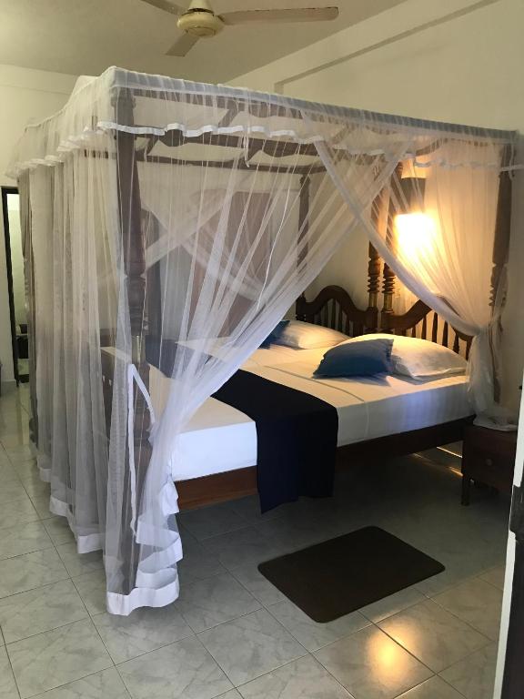 a bedroom with a canopy bed with white curtains at Unawatuna Beach Bungalow - in Unawatuna