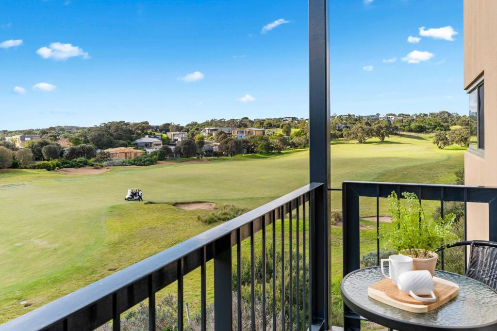 een balkon met een tafel en uitzicht op een golfbaan bij Fairway Views – Moonah Apartment 23 & 24 in Fingal