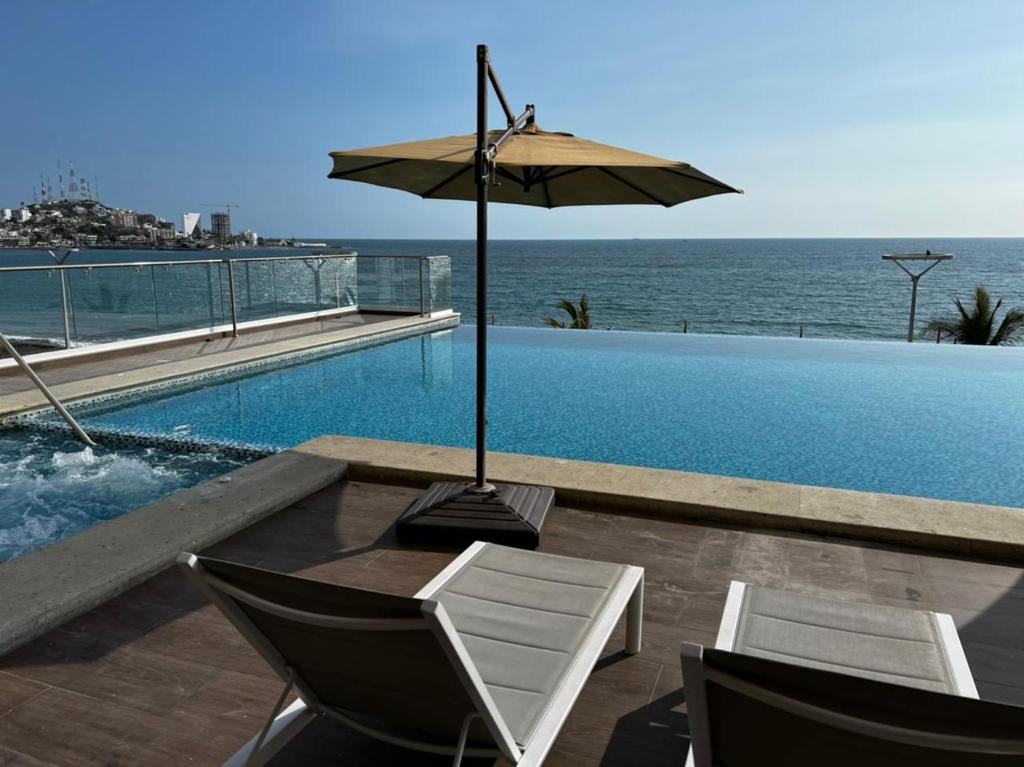 - Piscina con mesa, sombrilla y sillas en Luxury condo en Malecón, Alberca Infinity & Jacuzzi, en Mazatlán