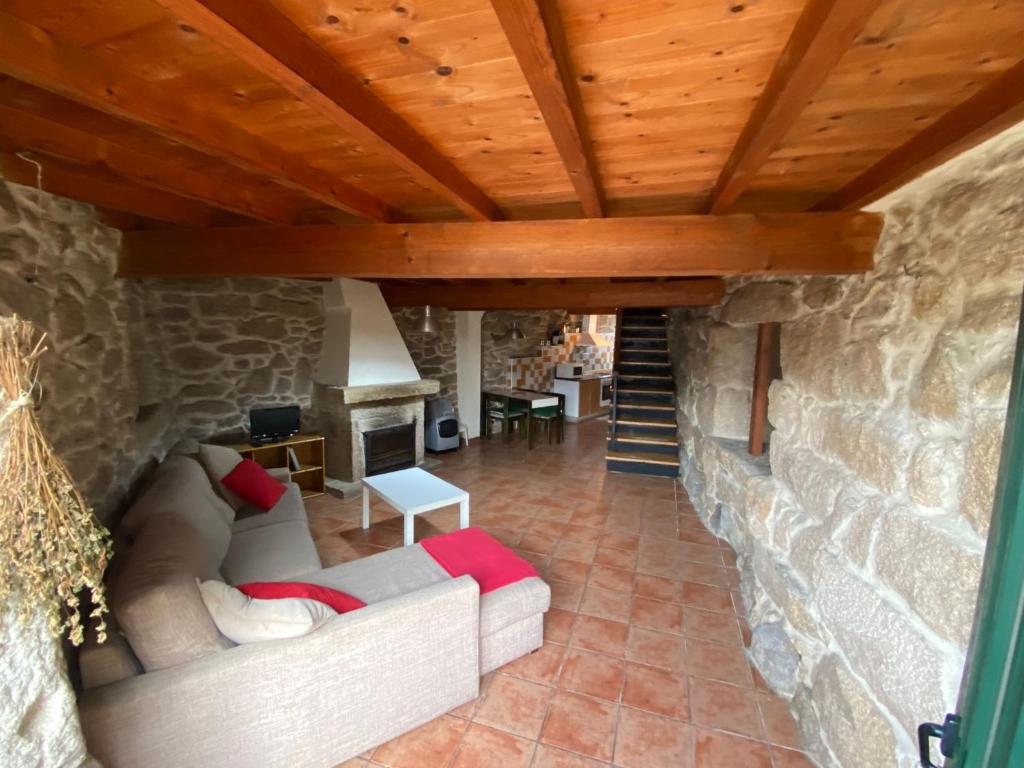 a living room with a couch and a stone wall at Casa da Vilaboa, Allariz in Allariz