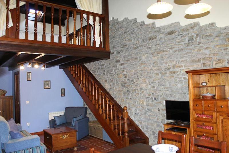 a living room with a staircase and a stone wall at Rodiles Rural Apartamentos in Selorio