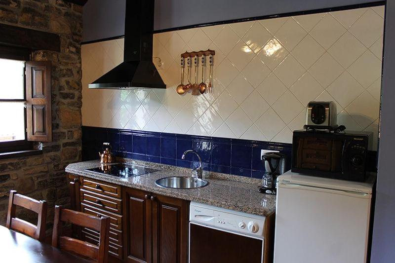 a kitchen with a sink and a refrigerator at Rodiles Rural Apartamentos in Selorio