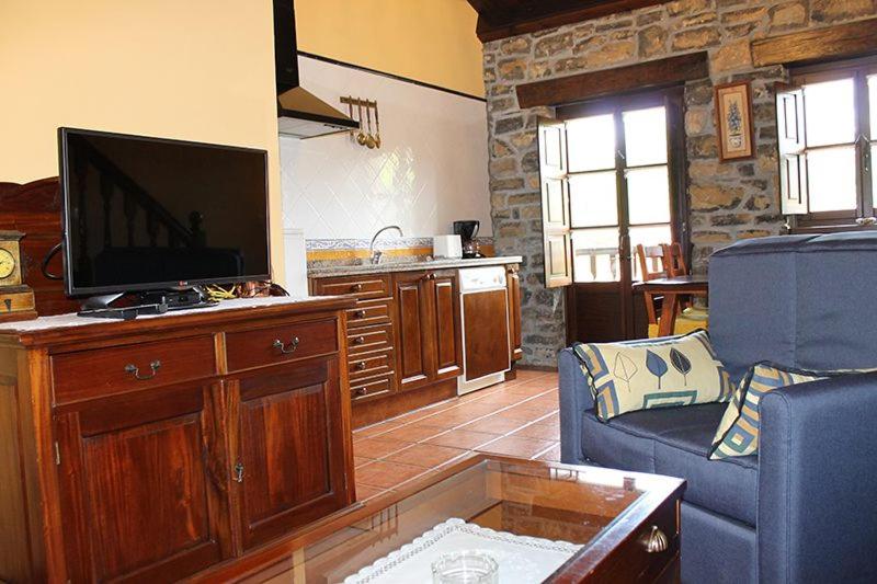 a living room with a flat screen tv and a couch at Rodiles Rural Apartamentos in Selorio