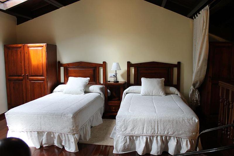 a bedroom with two beds with white sheets and wooden furniture at Rodiles Rural Apartamentos in Selorio