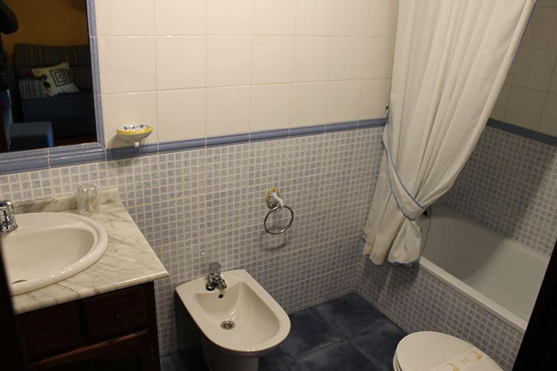 a bathroom with a sink and a toilet and a tub at Rodiles Rural Apartamentos in Selorio
