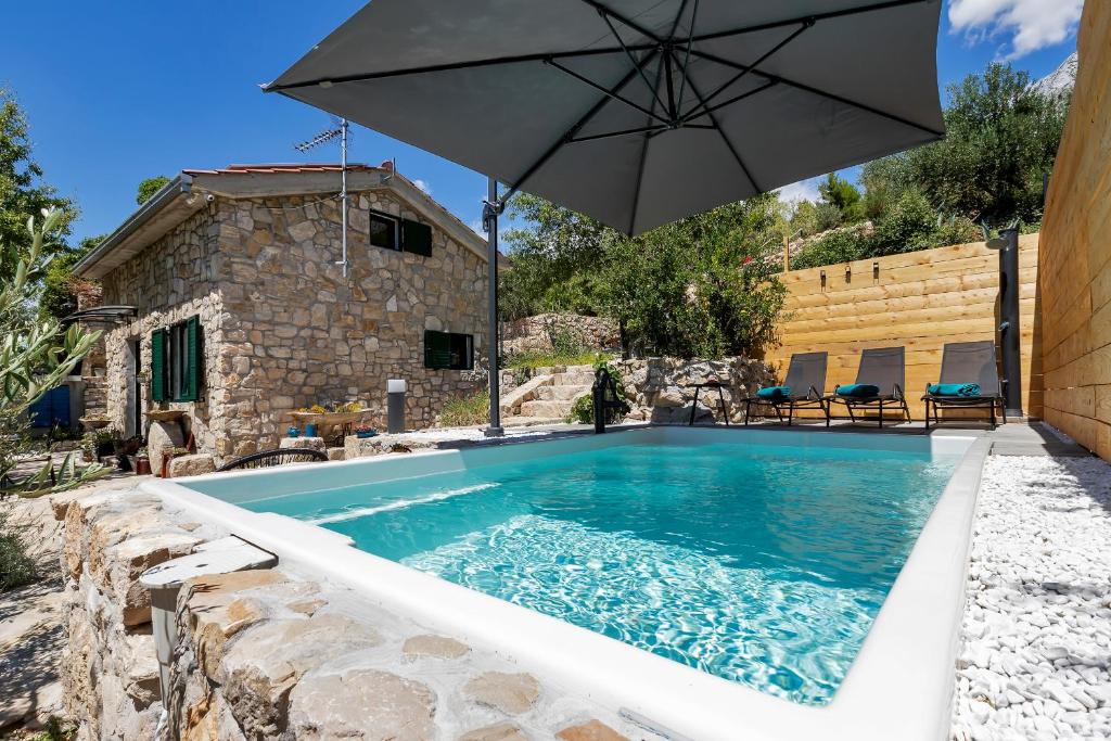 una piscina con sombrilla junto a una casa en Olive Garden, en Makarska