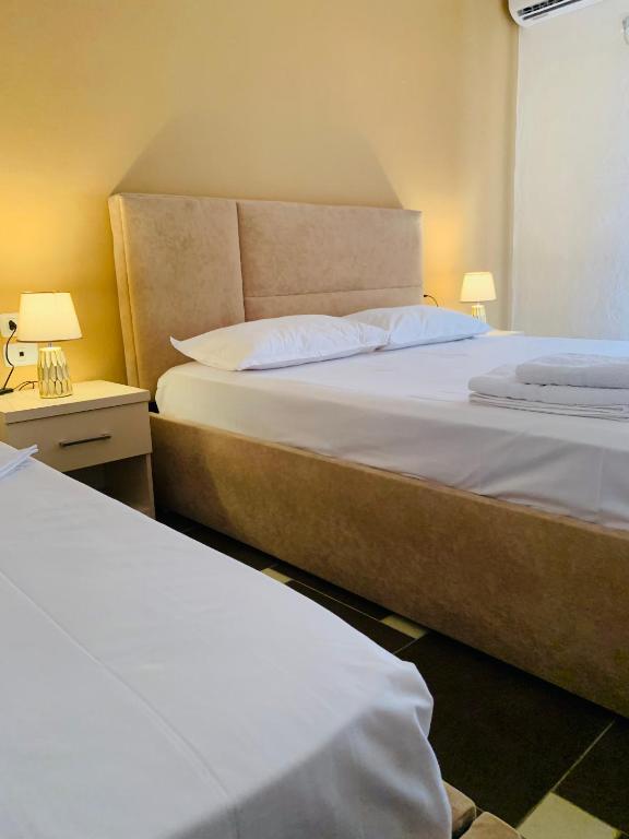 two beds in a room with two lamps on a table at Balkan Apartaments in Shëngjin
