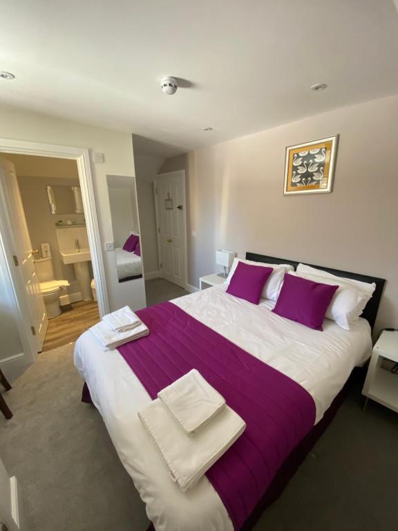 a bedroom with a large bed with purple and white pillows at The Swan @Old Stratford in Milton Keynes
